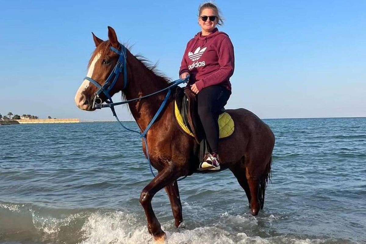 una dona muntant a cavall a la platja