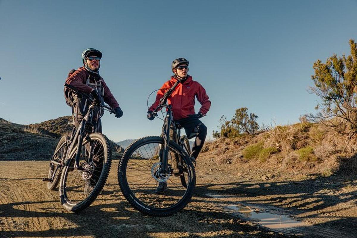 two men riding bikes on a dirt road