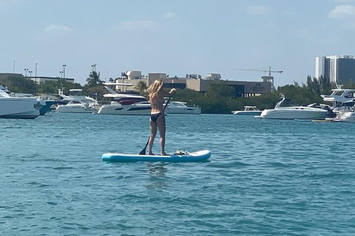 Una niña está parada sobre una tabla de remo en el agua.