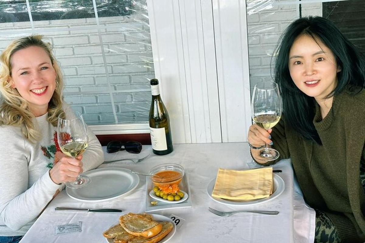to kvinner sitter ved et bord med glass vin