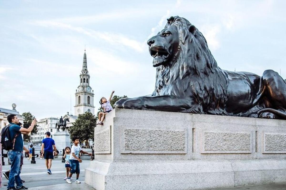 Una estatua de un león con gente caminando a su alrededor.