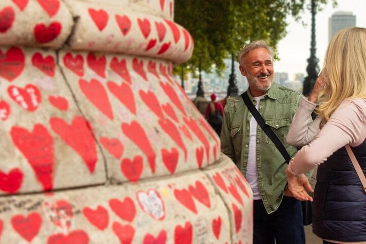 a man and a woman standing next to a heart statue