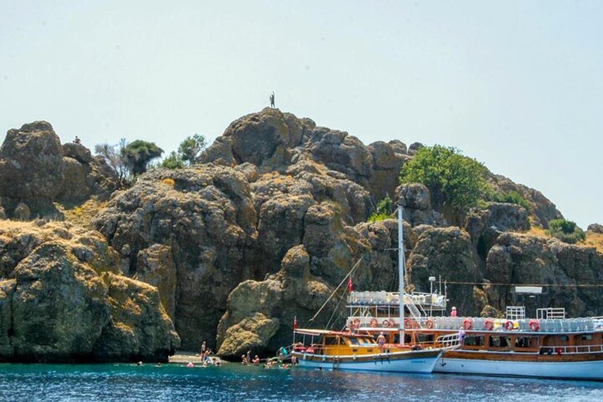 two boats in the water next to a rocky island