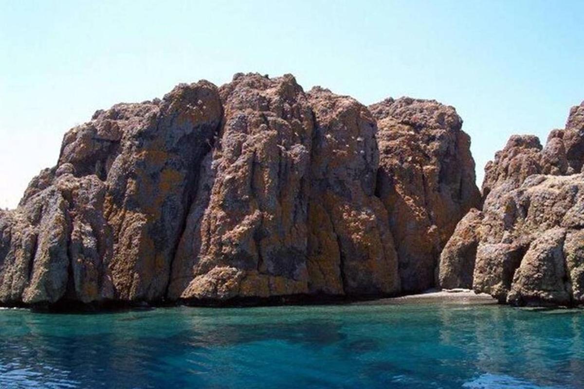a large rocky island in the ocean with blue water