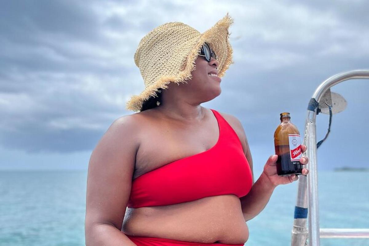 eine schwangere Frau in einem roten Bikini mit einer Flasche Alkohol