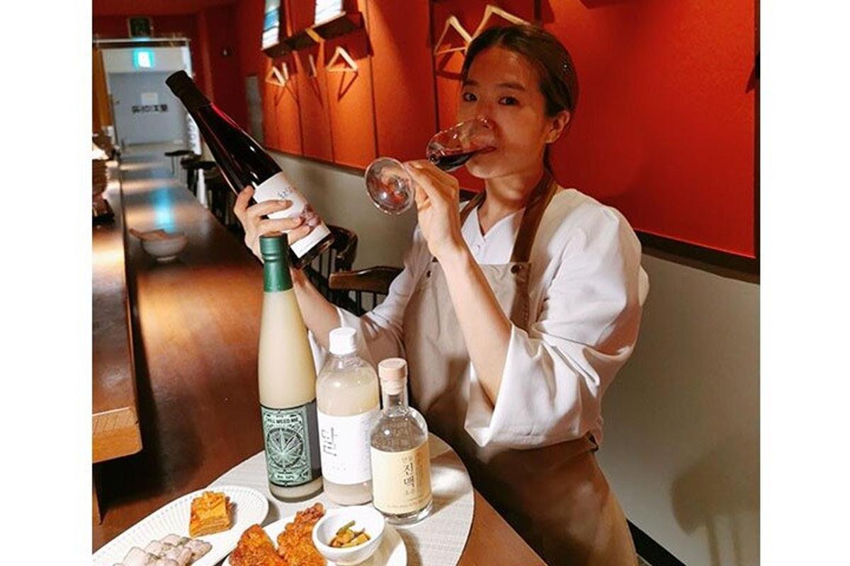 테이블에 앉아 와인 한 병을 마시고 있는 여자