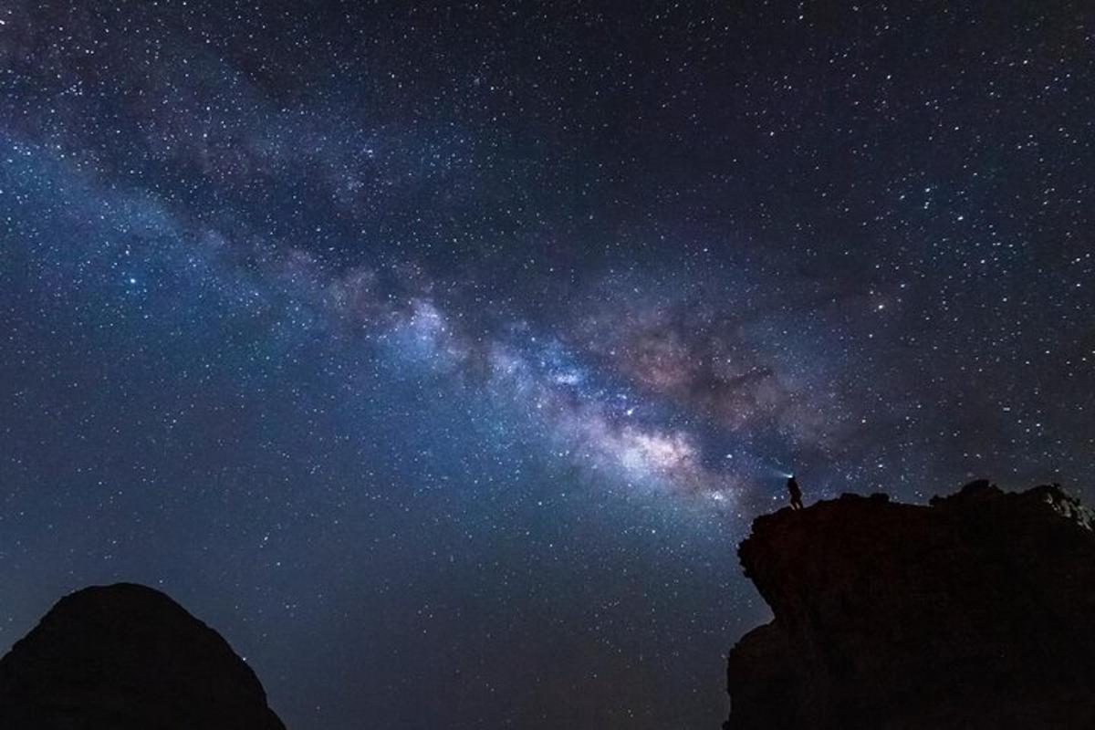 a starry sky with a person standing on a mountain