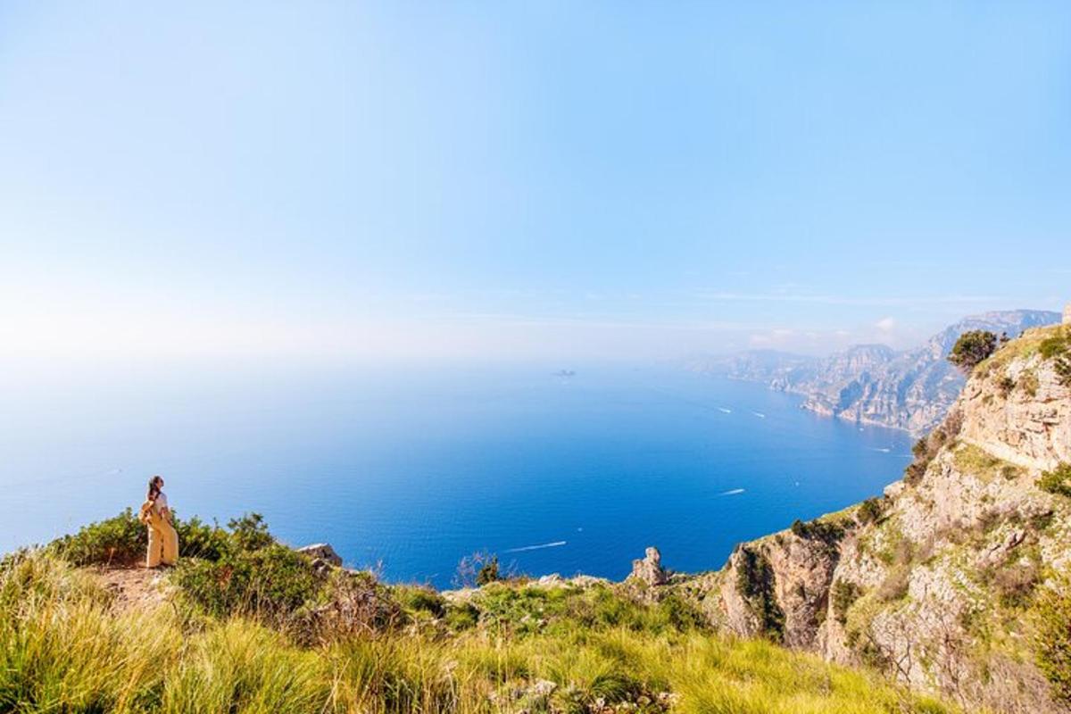 oseba, ki sedi na vrhu gore in gleda na ocean