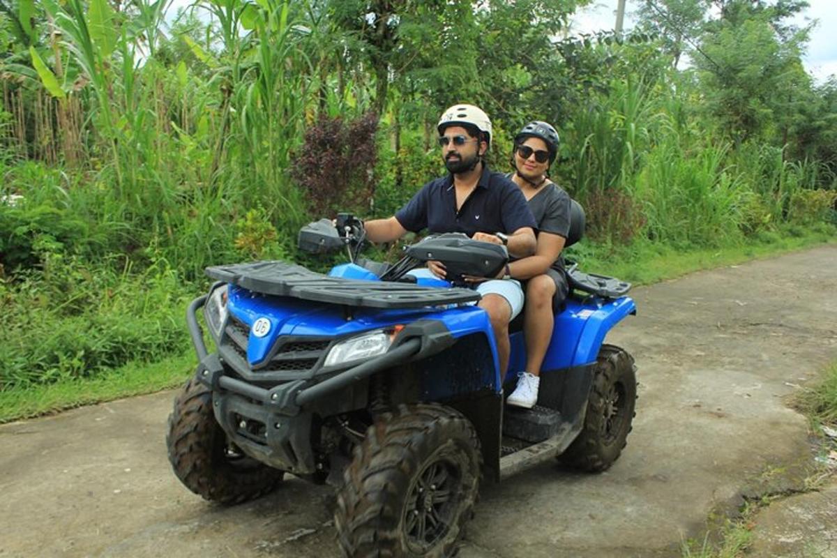 dos homes que viatgen en un quad per una carretera de terra