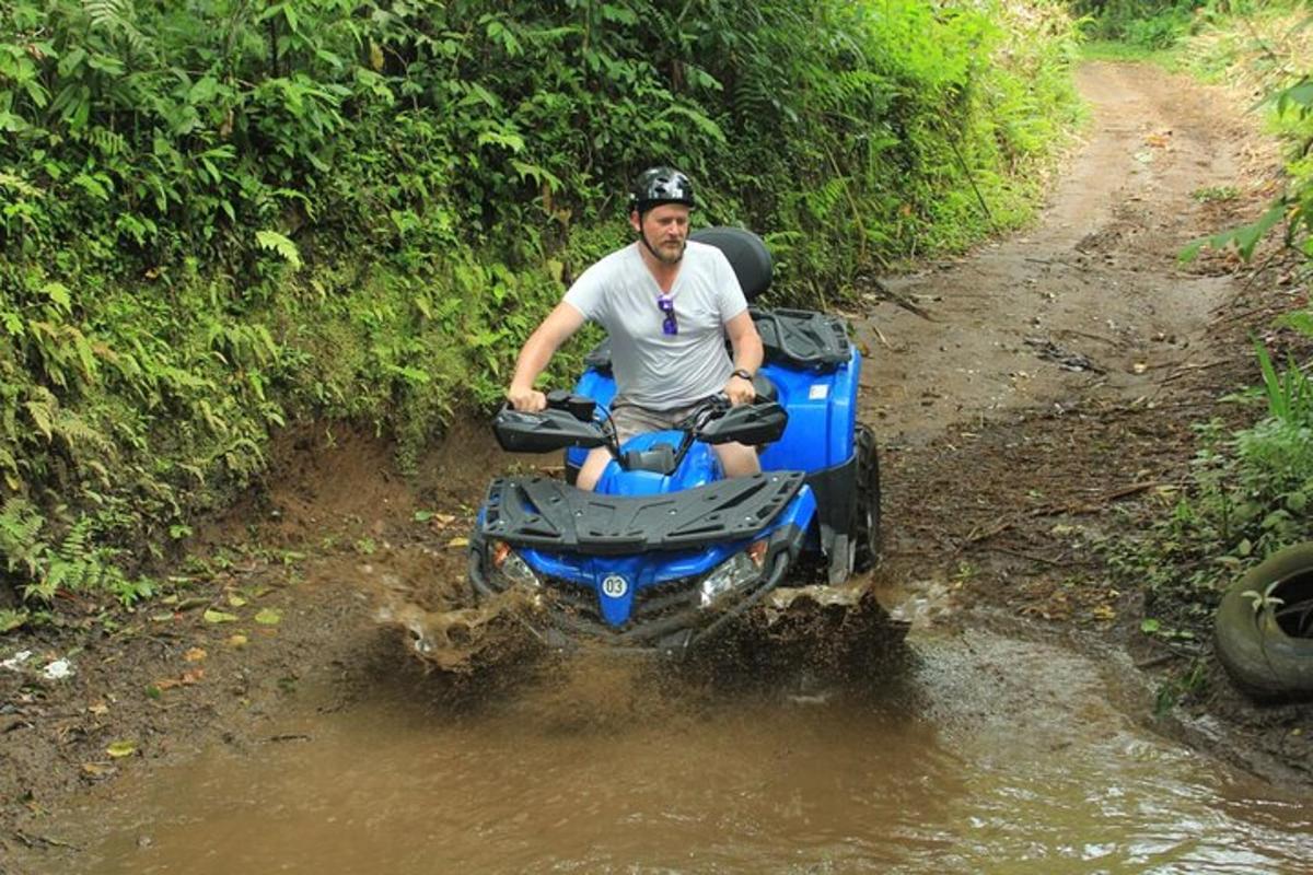 un home que condueix un quad per un camí fangós