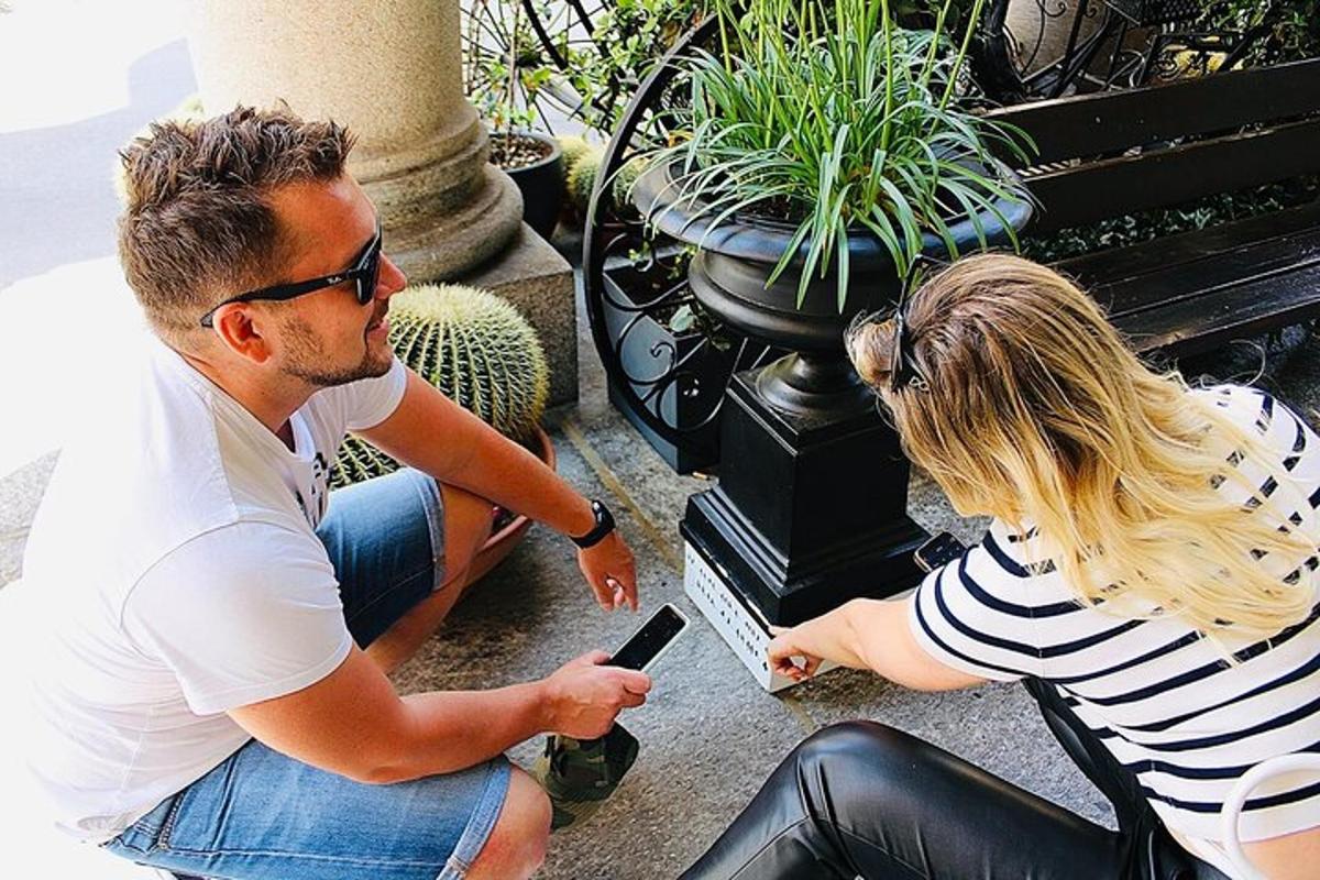 un home i una dona asseguts en un banc mirant un telèfon mòbil