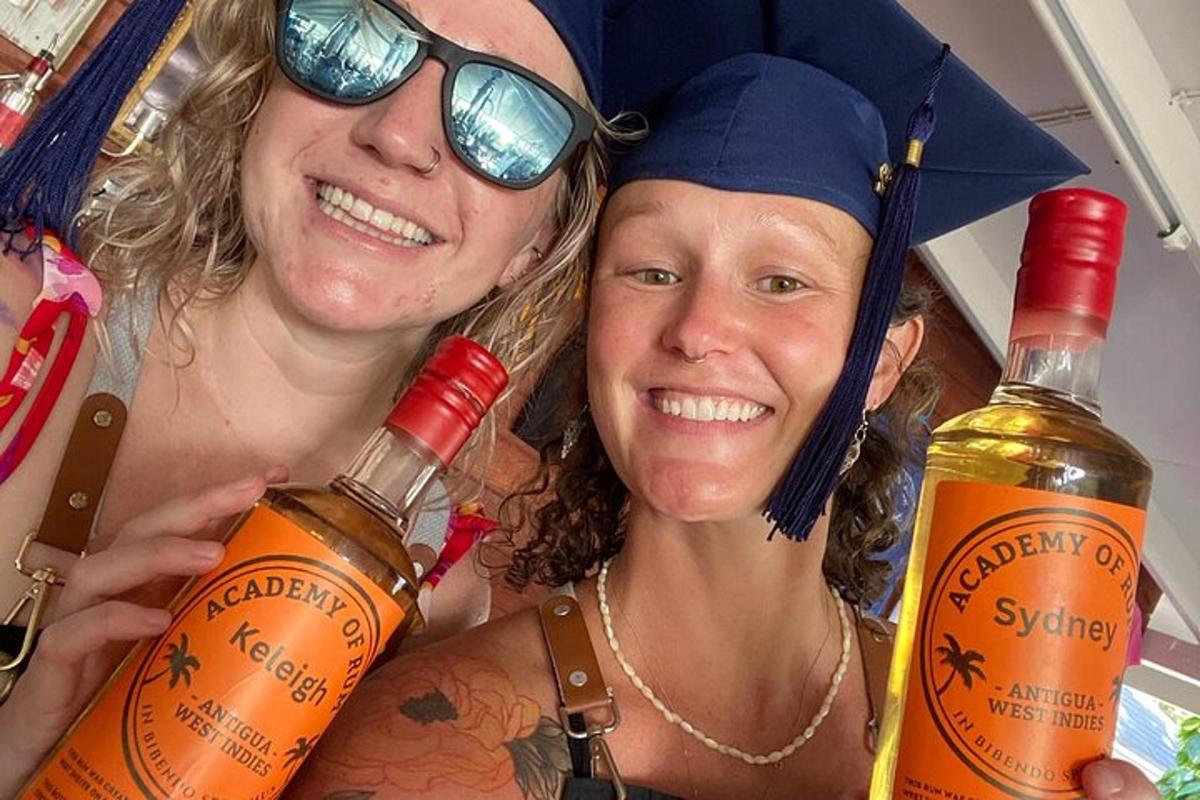 two women in graduation hats holding bottles of wine