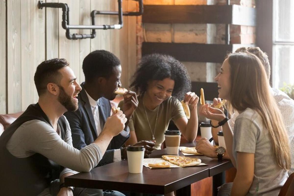 un grup de persones assegudes a una taula menjant pizza