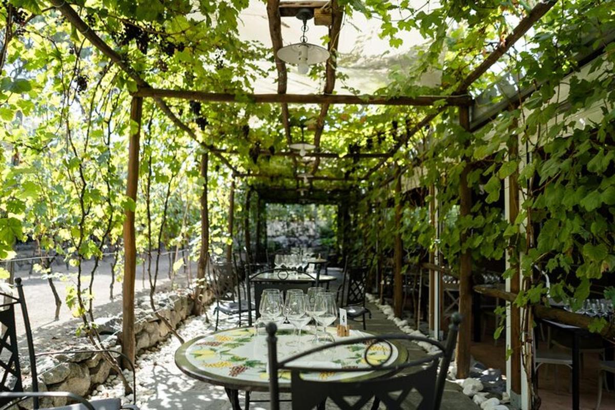 terasz asztalokkal és székekkel egy pergola alatt