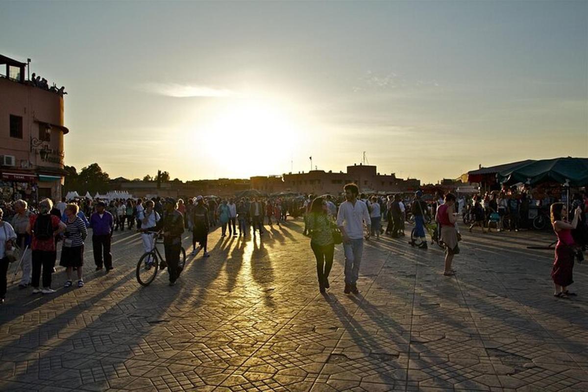uma multidão de pessoas caminhando pela rua ao pôr do sol