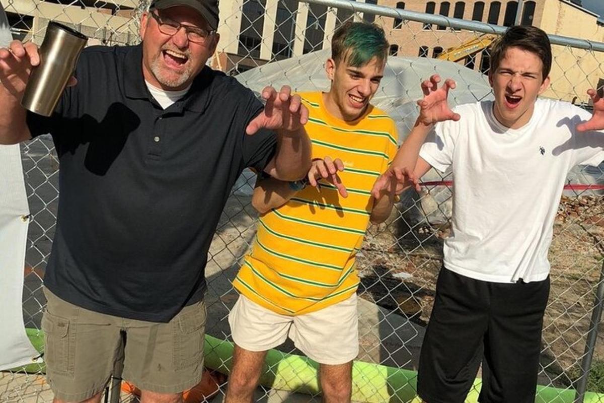 フェンスの横に立っている3人の男性のグループ