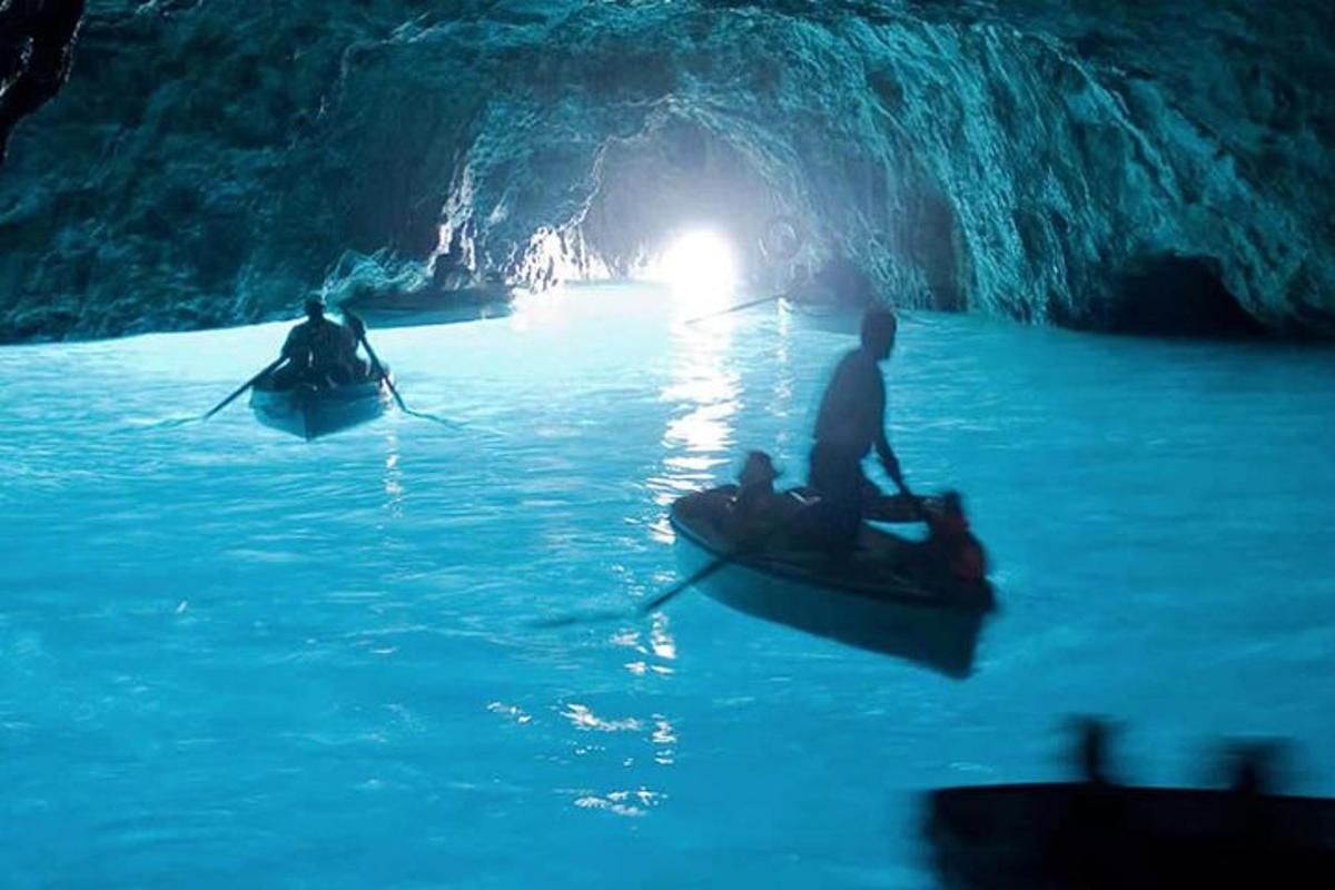 duas pessoas em barcos em uma caverna azul