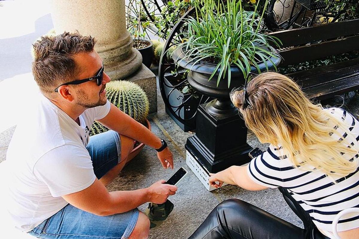 muž a žena sedící na lavičce a dívající se na mobilní telefon