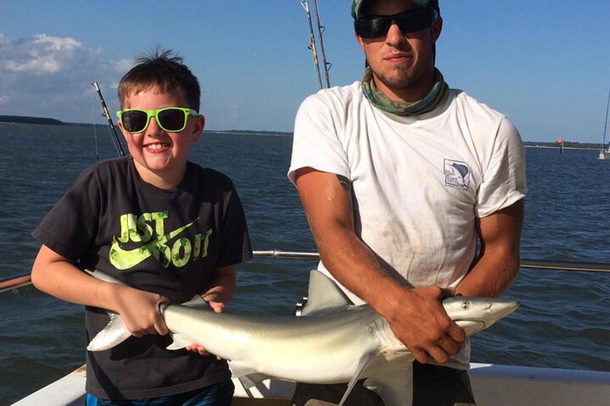 a man and a boy holding a shark on a boat