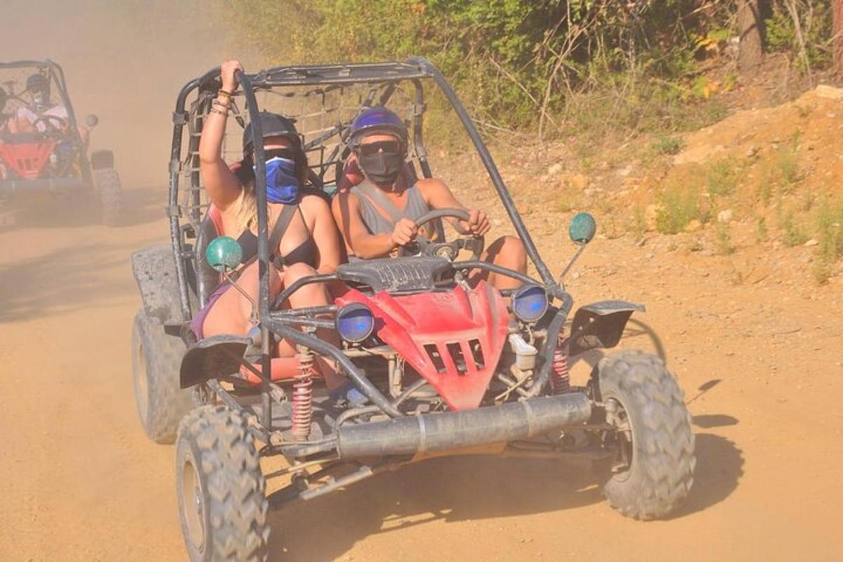 dues persones en un quad per una carretera de terra
