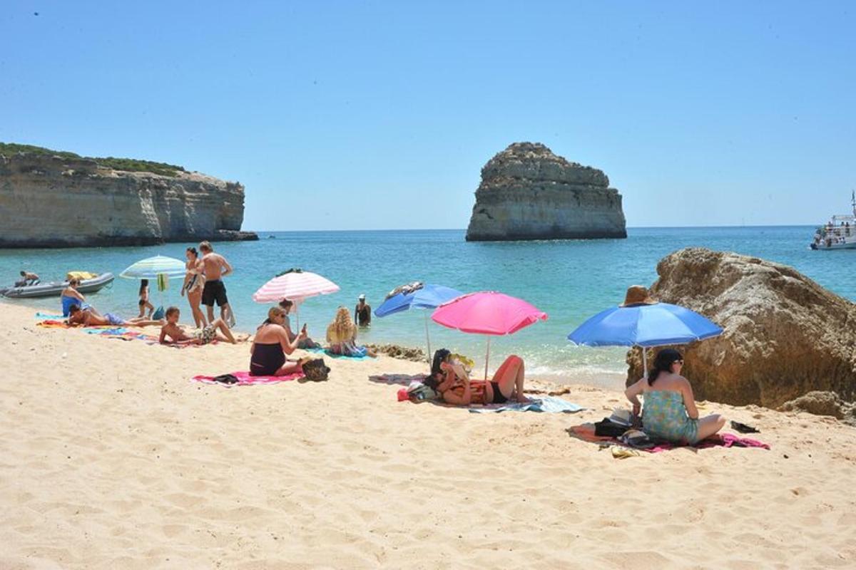 un grup de persones assegudes a la platja amb para-sols