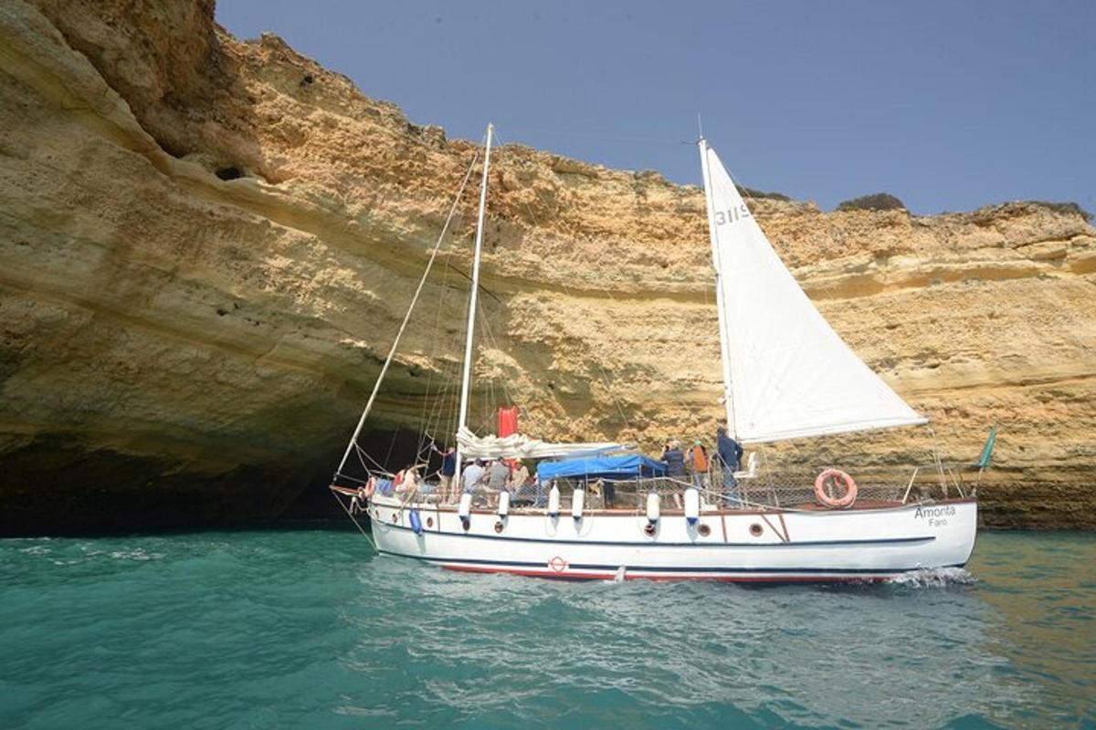 un vaixell blanc a l'aigua al costat d'una cova