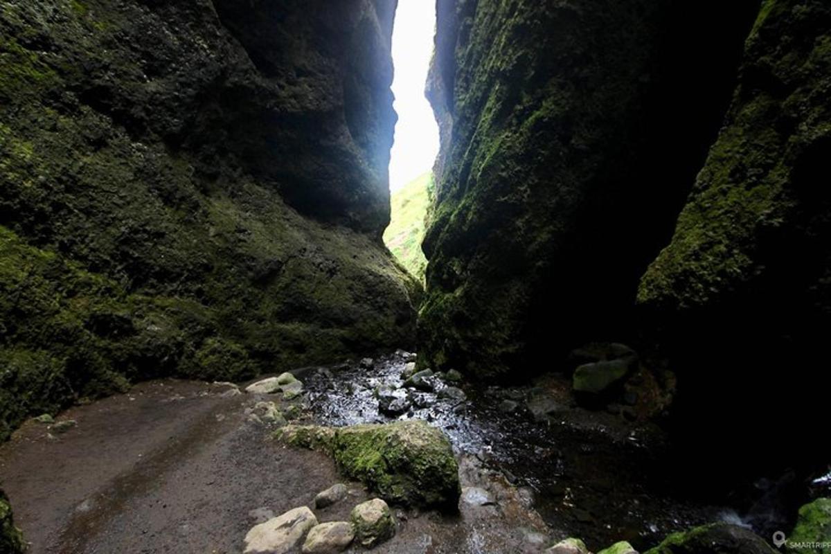 a cave with a waterfall in the middle of a canyon