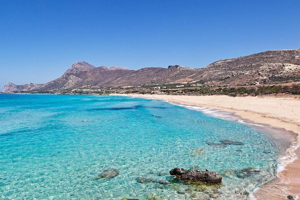 una platja amb aigües blaves i muntanyes al fons