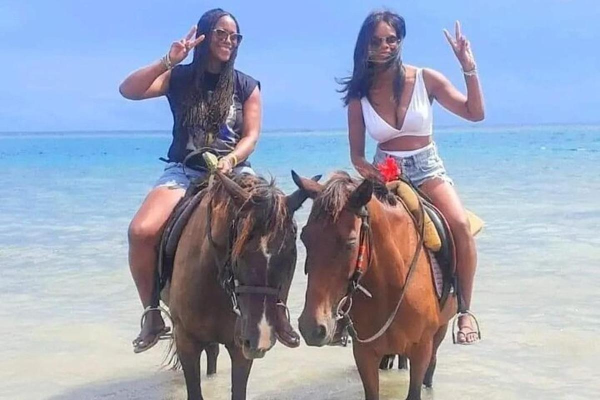 doi oameni călăresc cai pe plajă