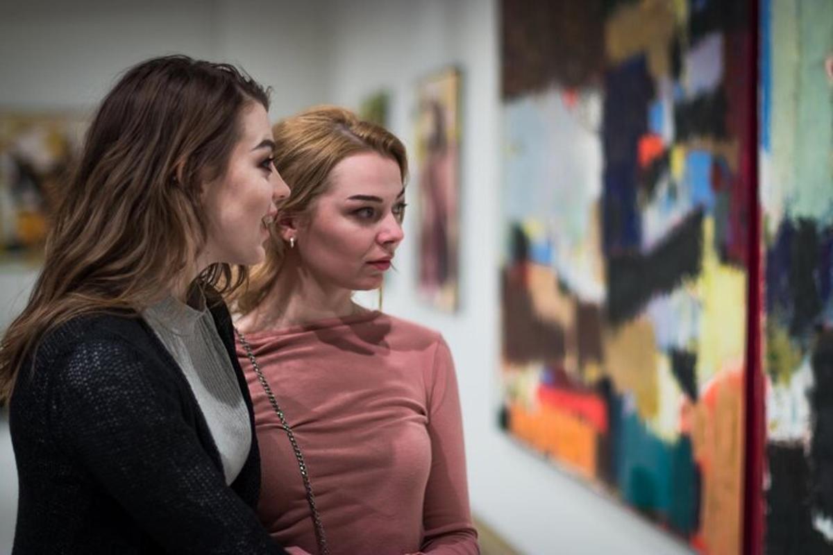 tvær konur standa hlið við hlið og horfa á málverk