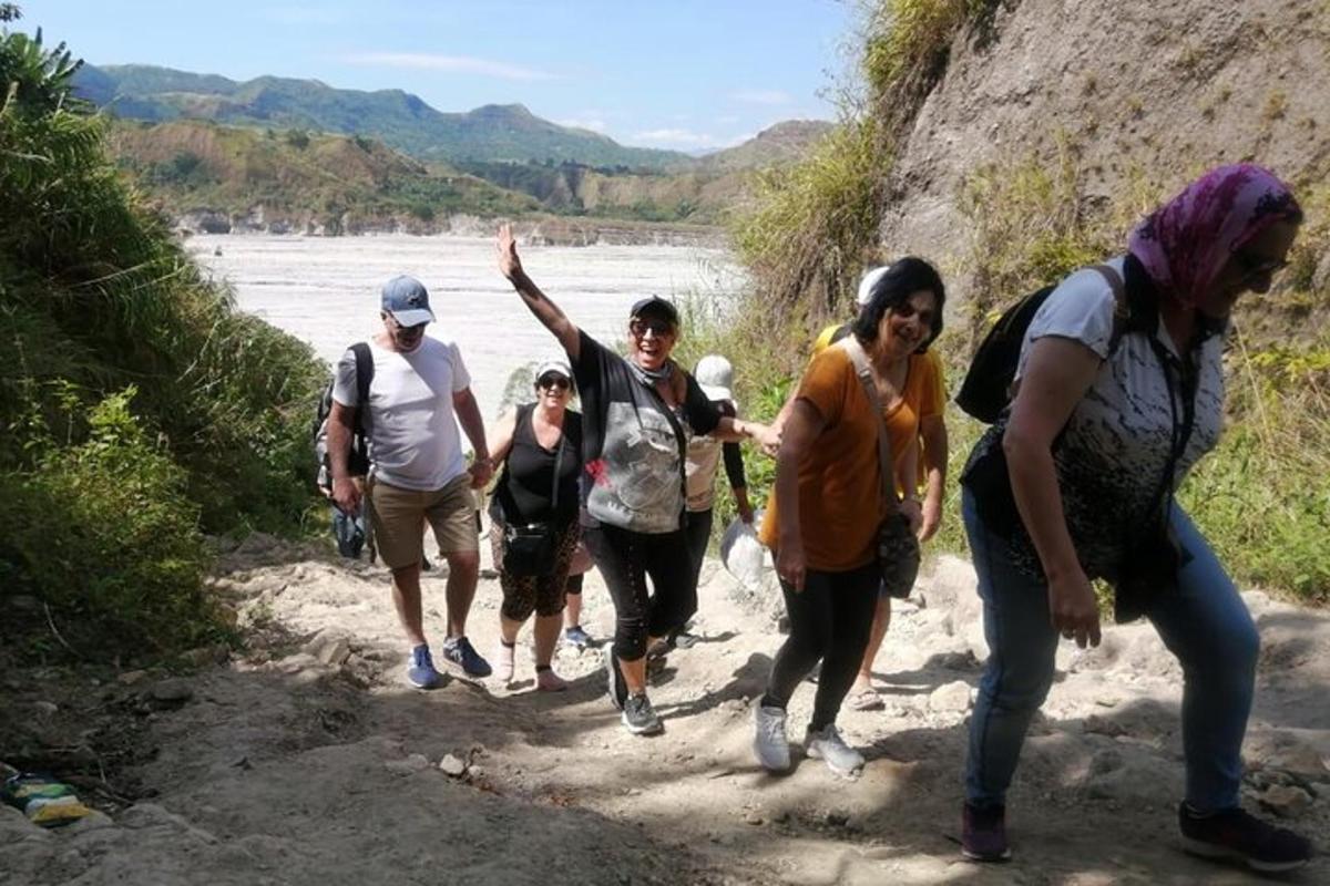 a group of people walking down a trail near a river
