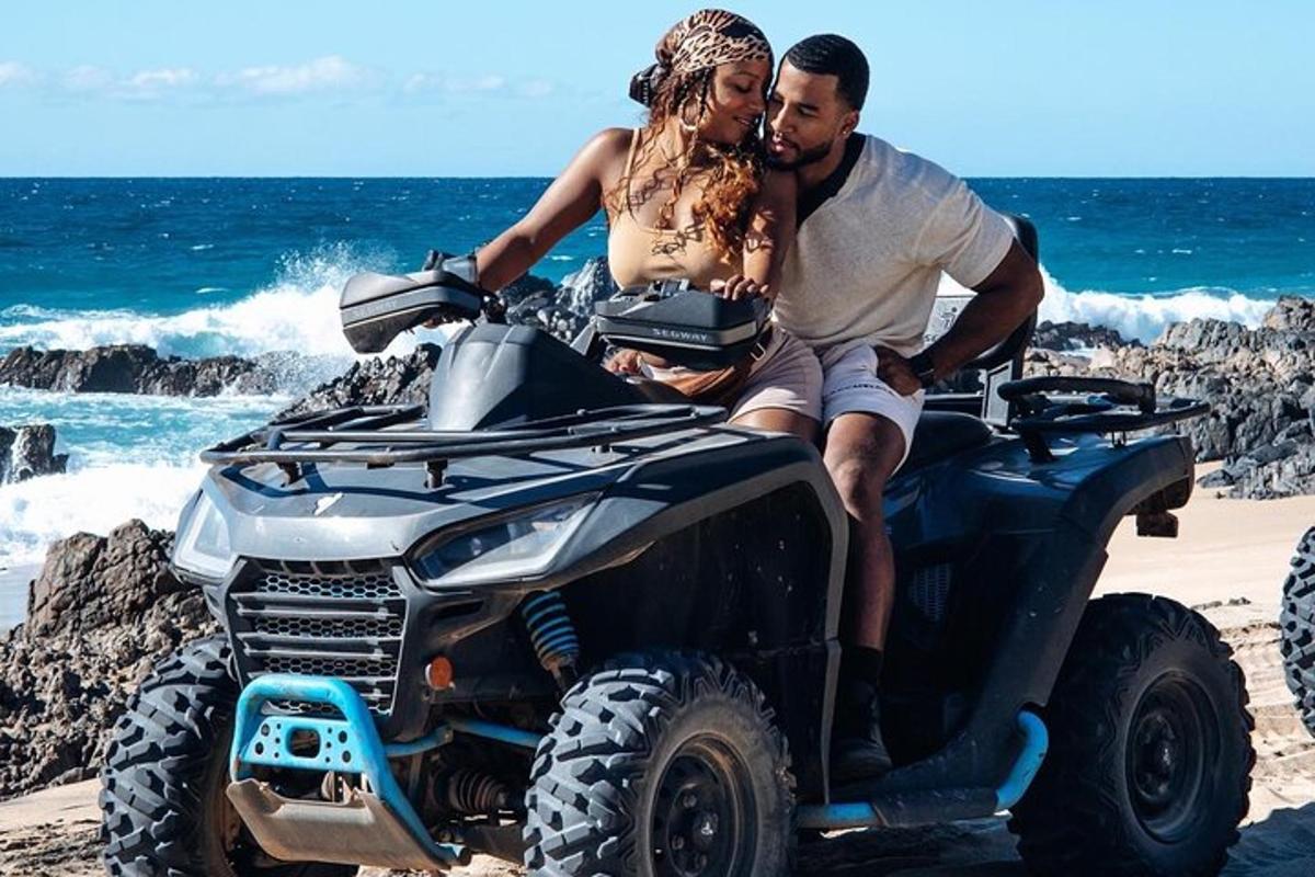 un uomo e una donna seduti su un quad sulla spiaggia