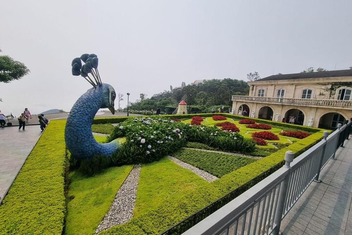 um jardim com uma estátua de pavão em frente a um prédio