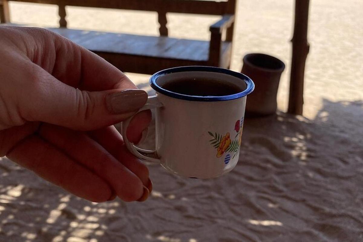 uma pessoa segurando uma xícara de café sobre uma mesa