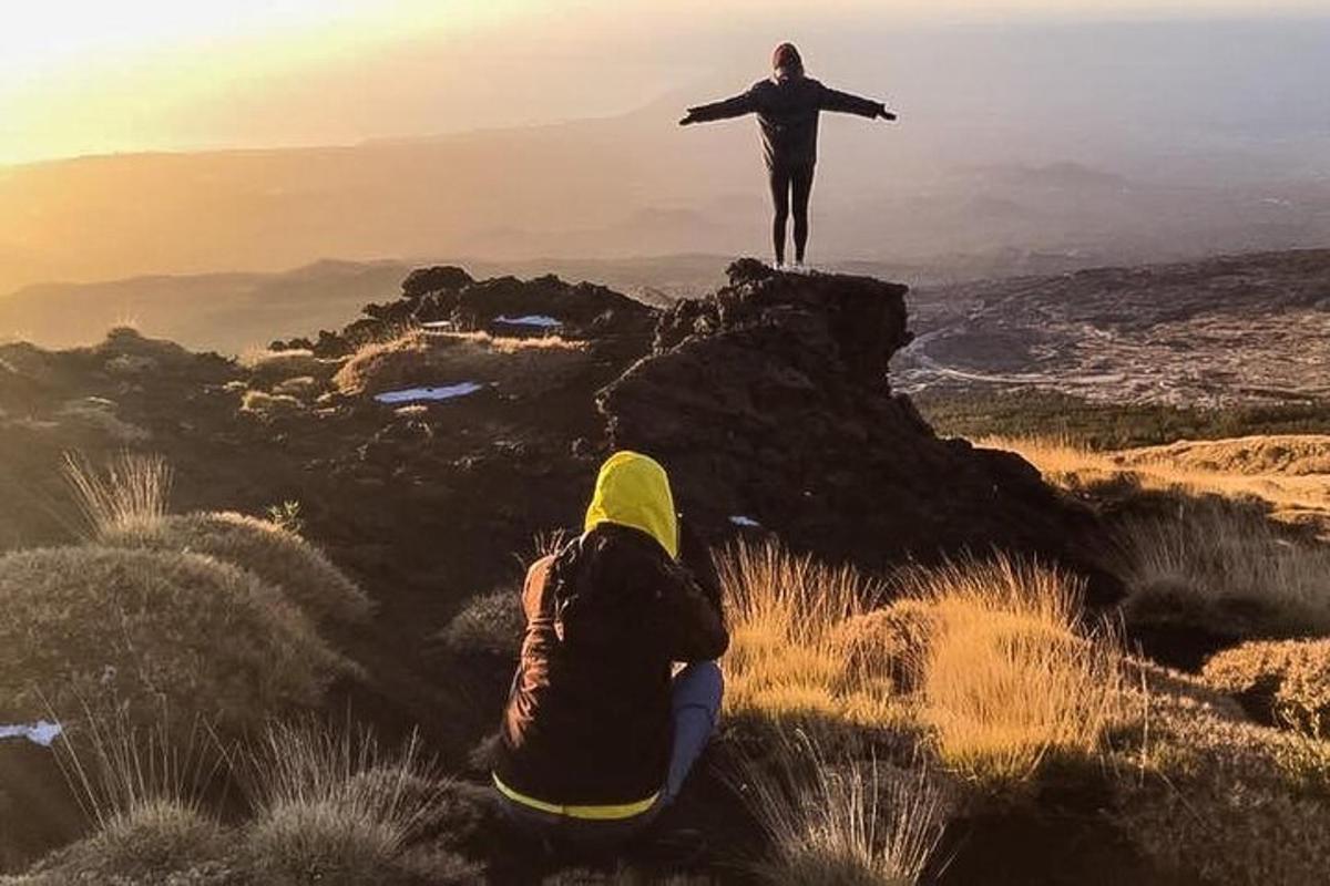 una persona in piedi sulla cima di una montagna con le braccia tese