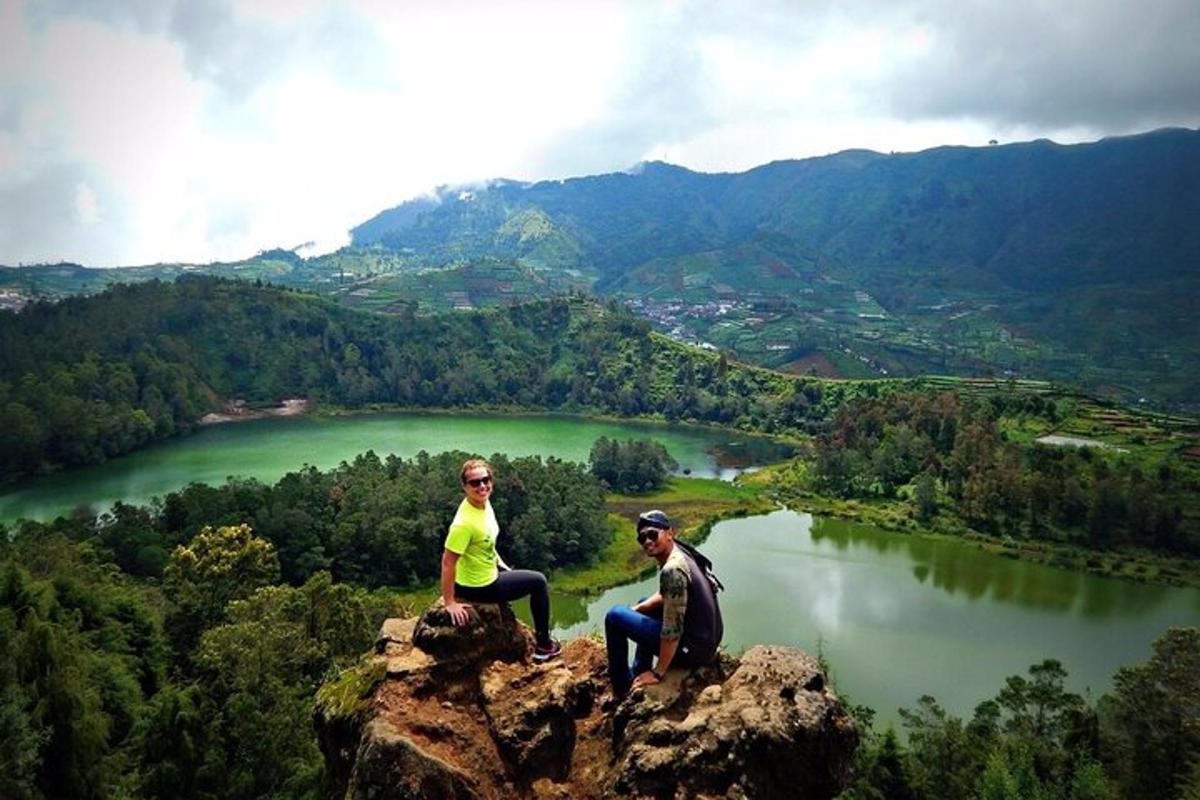 dua orang duduk di atas batu yang menghadap ke tasik