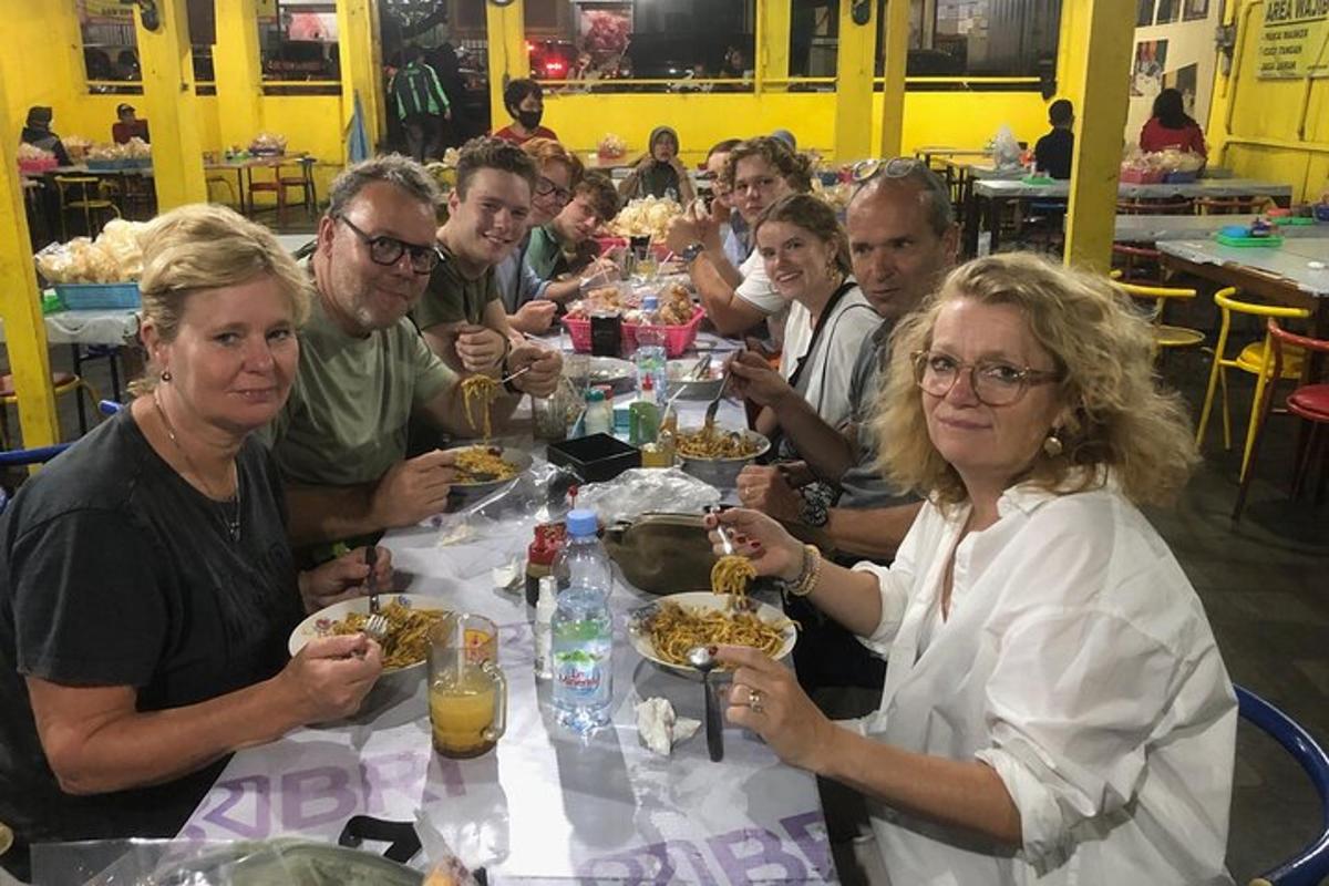 grupp inimesi istub laua taga ja sööb toitu