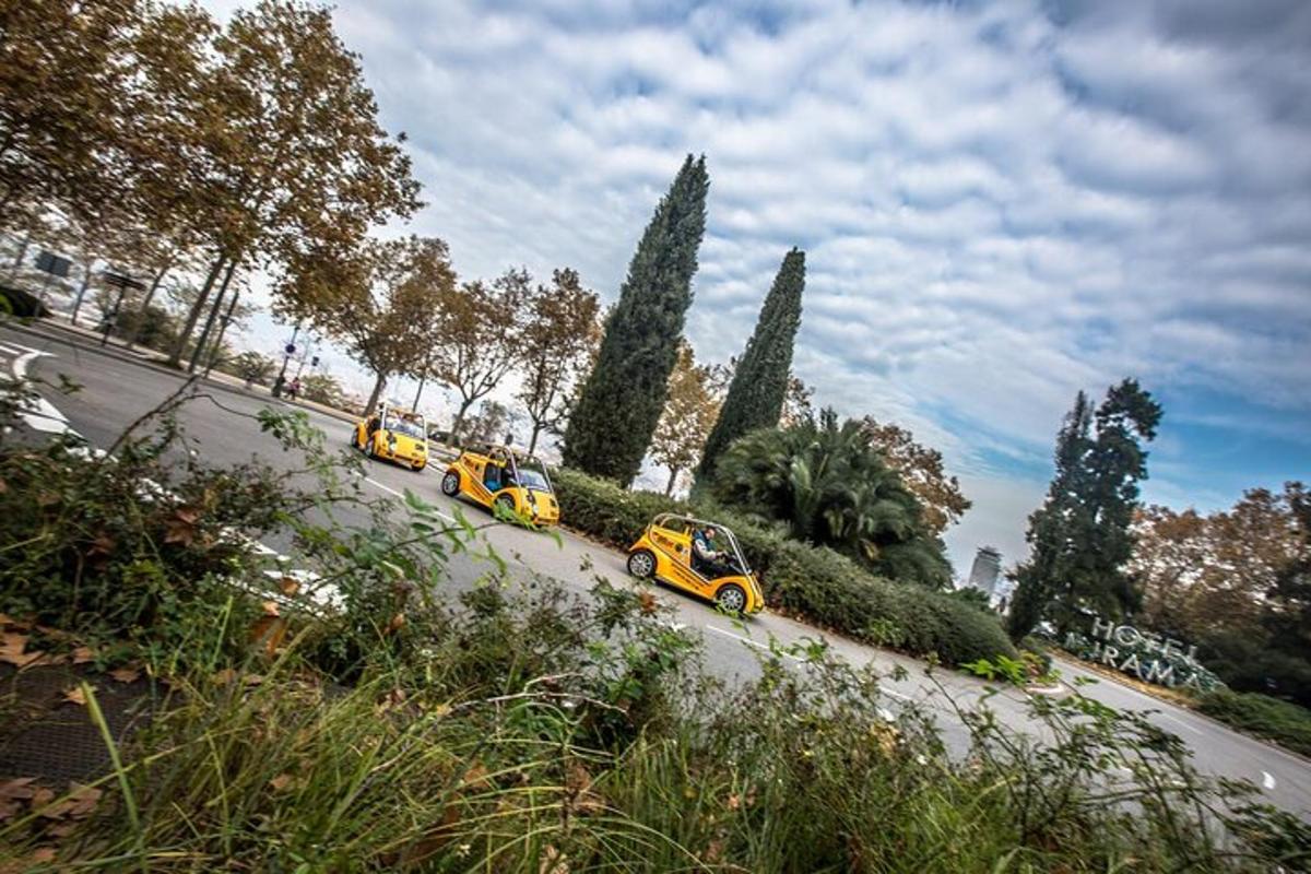 Un grupo de coches circulando por una calle con árboles.