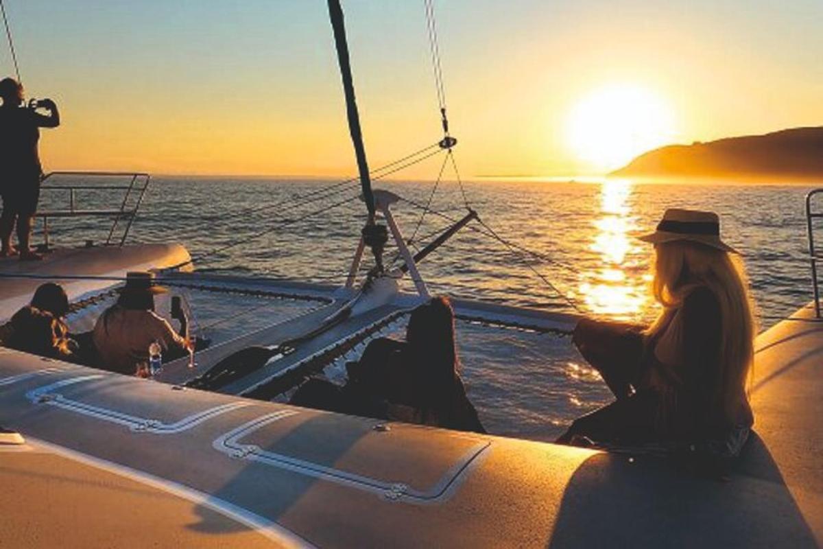 un gruppo di persone sedute su una barca al tramonto