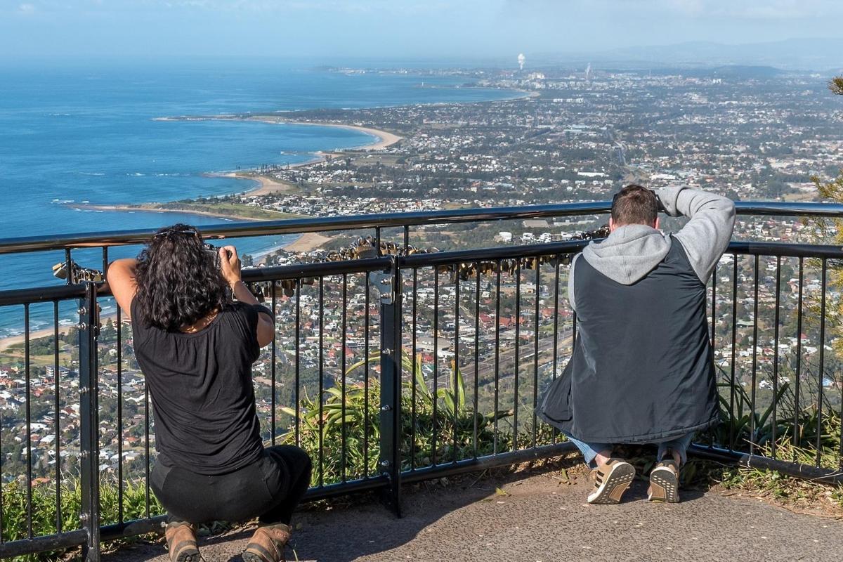 Dos personas tomando fotografías del océano desde un mirador.