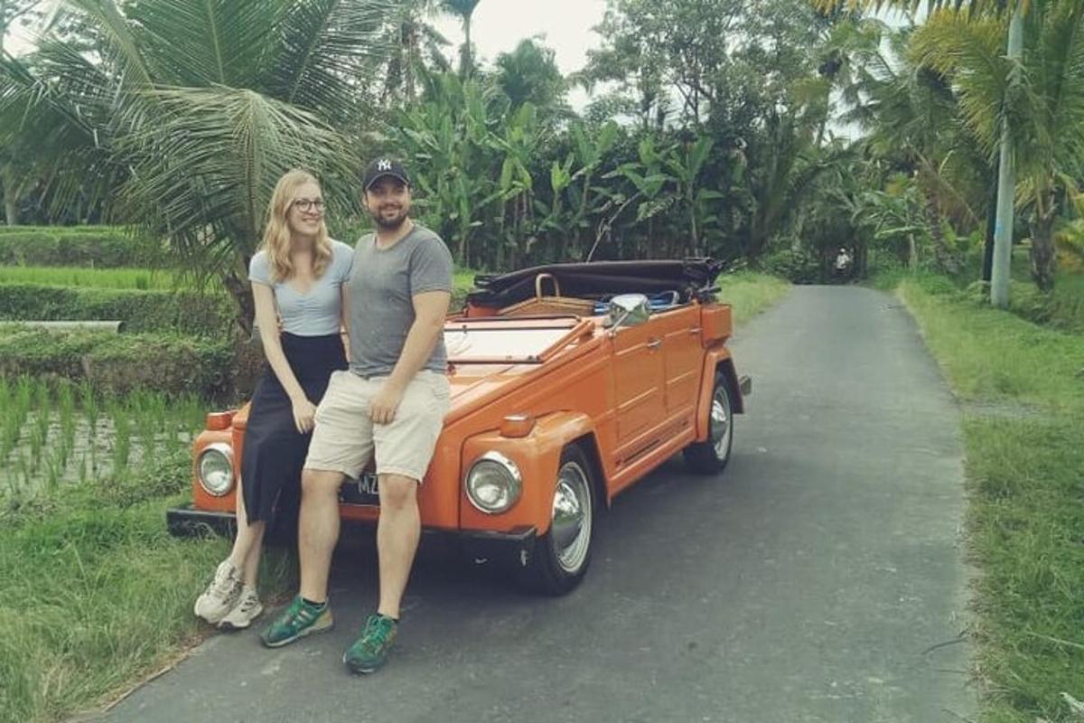 um homem e uma mulher sentados na parte de trás de um carro laranja