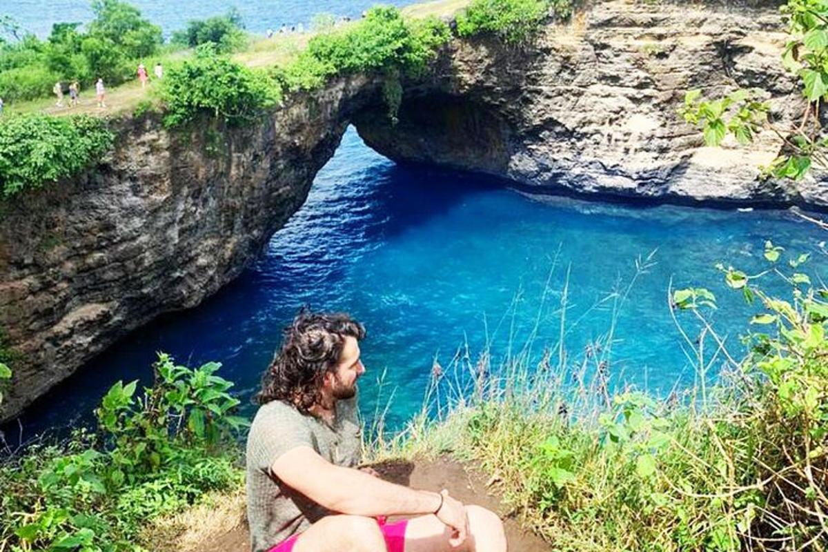 žena sediaca na útese pri vodnej ploche