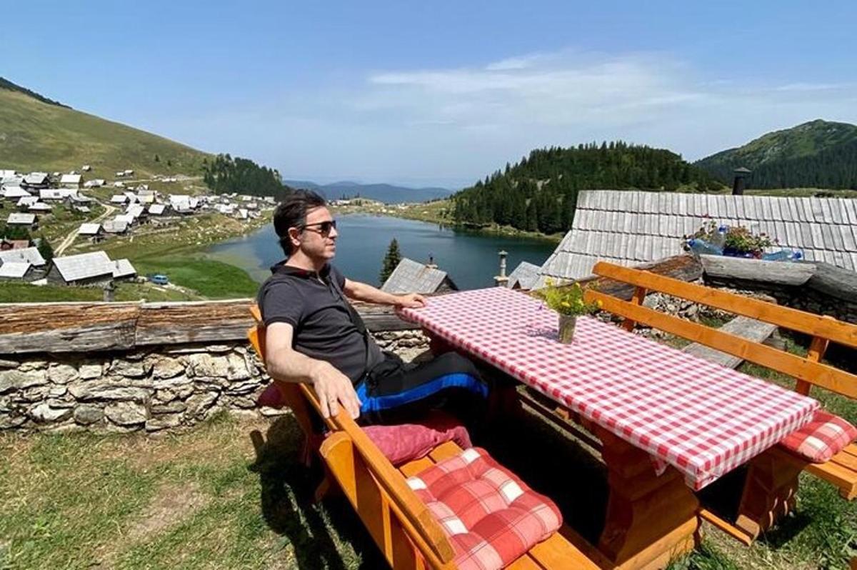 un bărbat așezat la o masă de picnic cu vedere la un râu