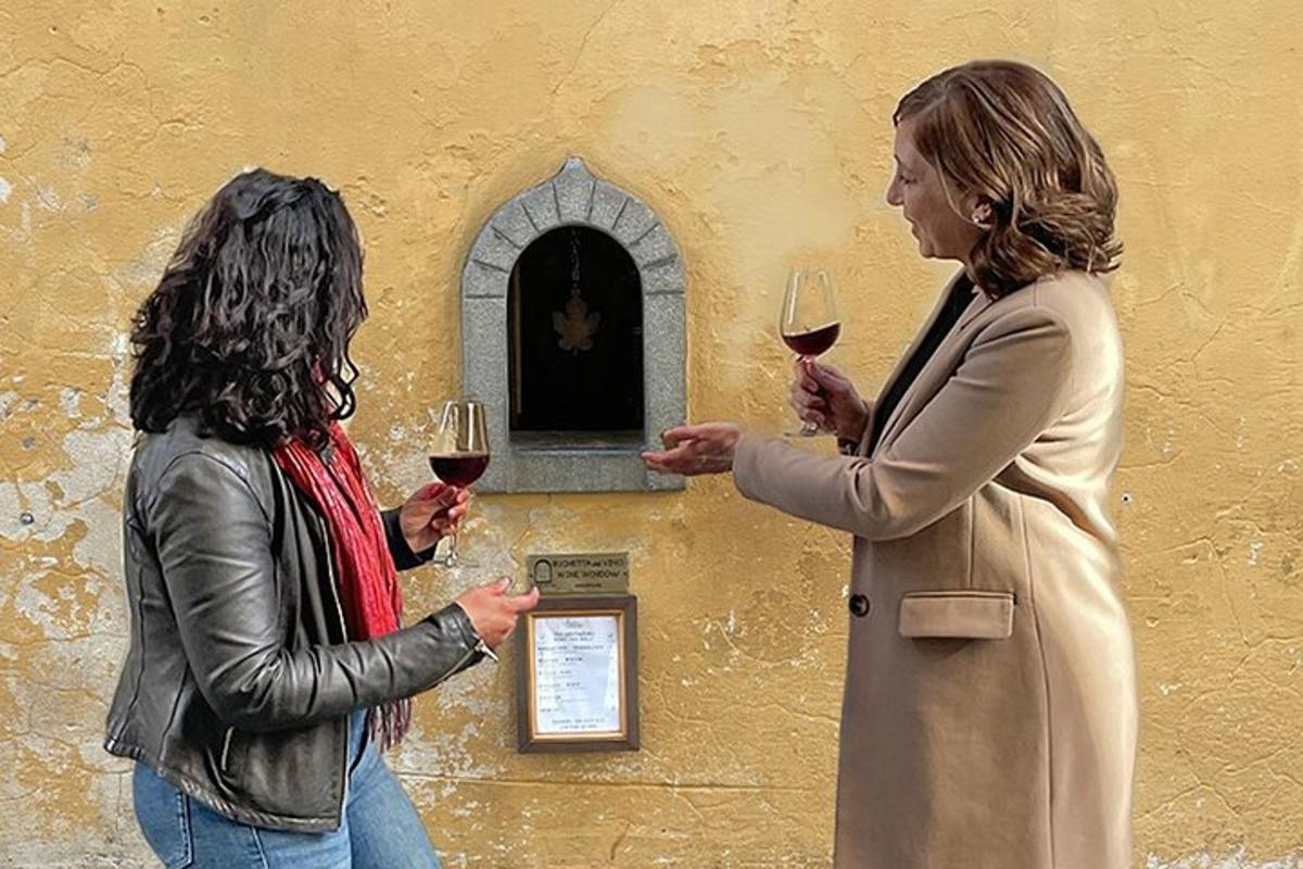 Dos mujeres sosteniendo copas de vino frente a una pared