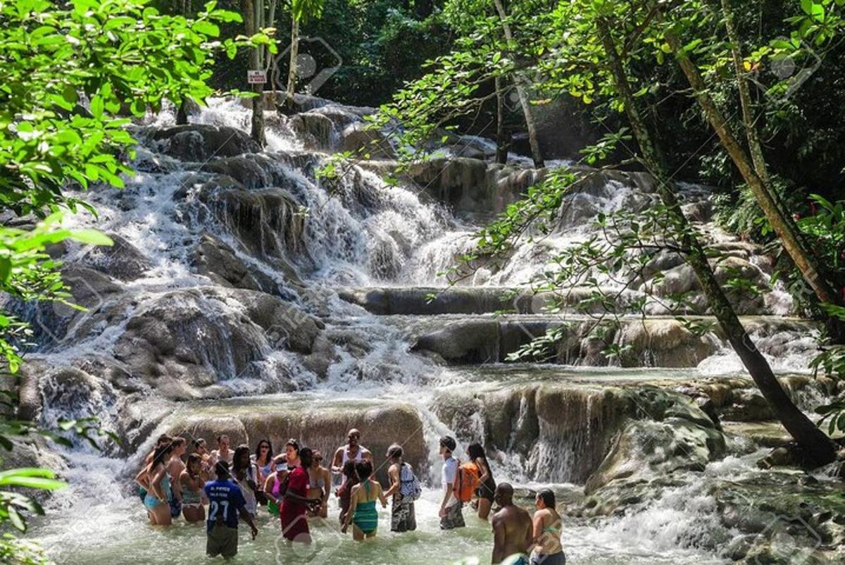 sekumpulan orang berdiri di dalam air terjun