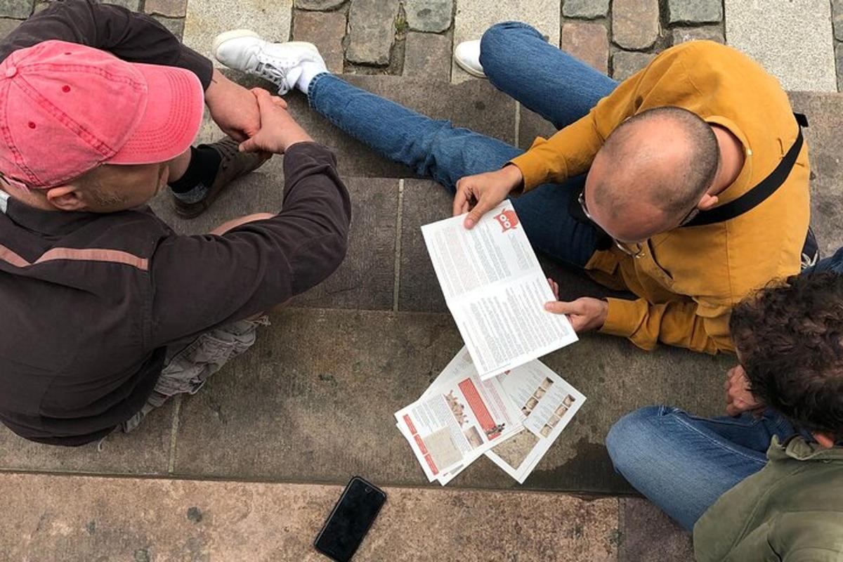 hópur fólks situr á tröppunum og horfir á dagblað