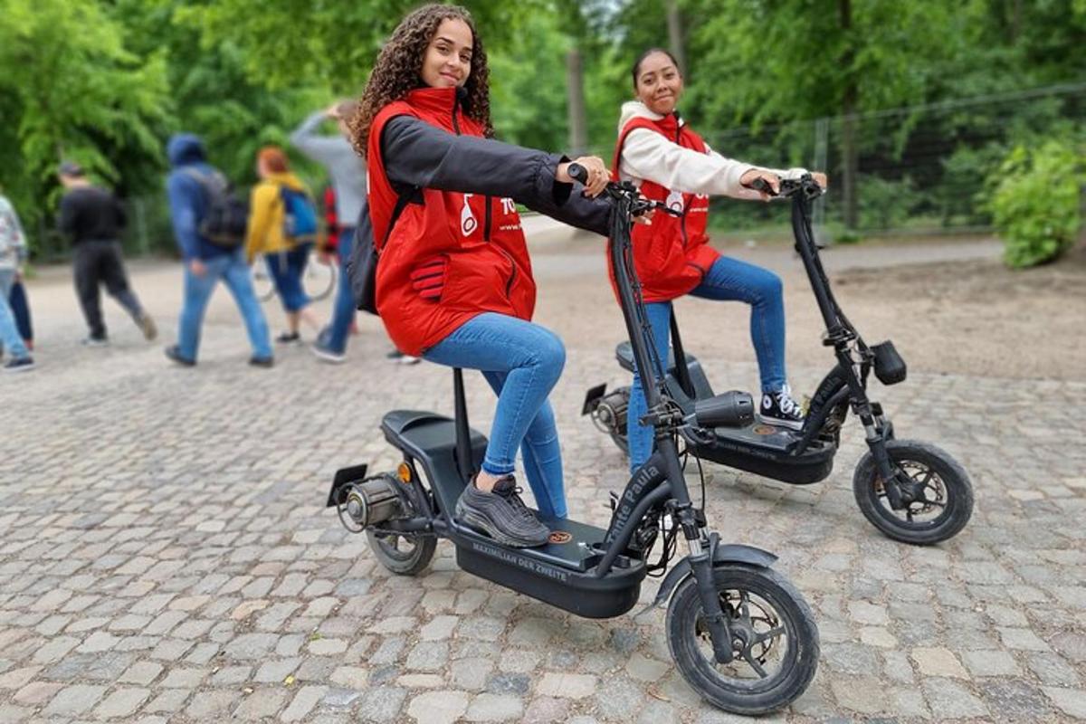 two girls are riding on an electric scooter