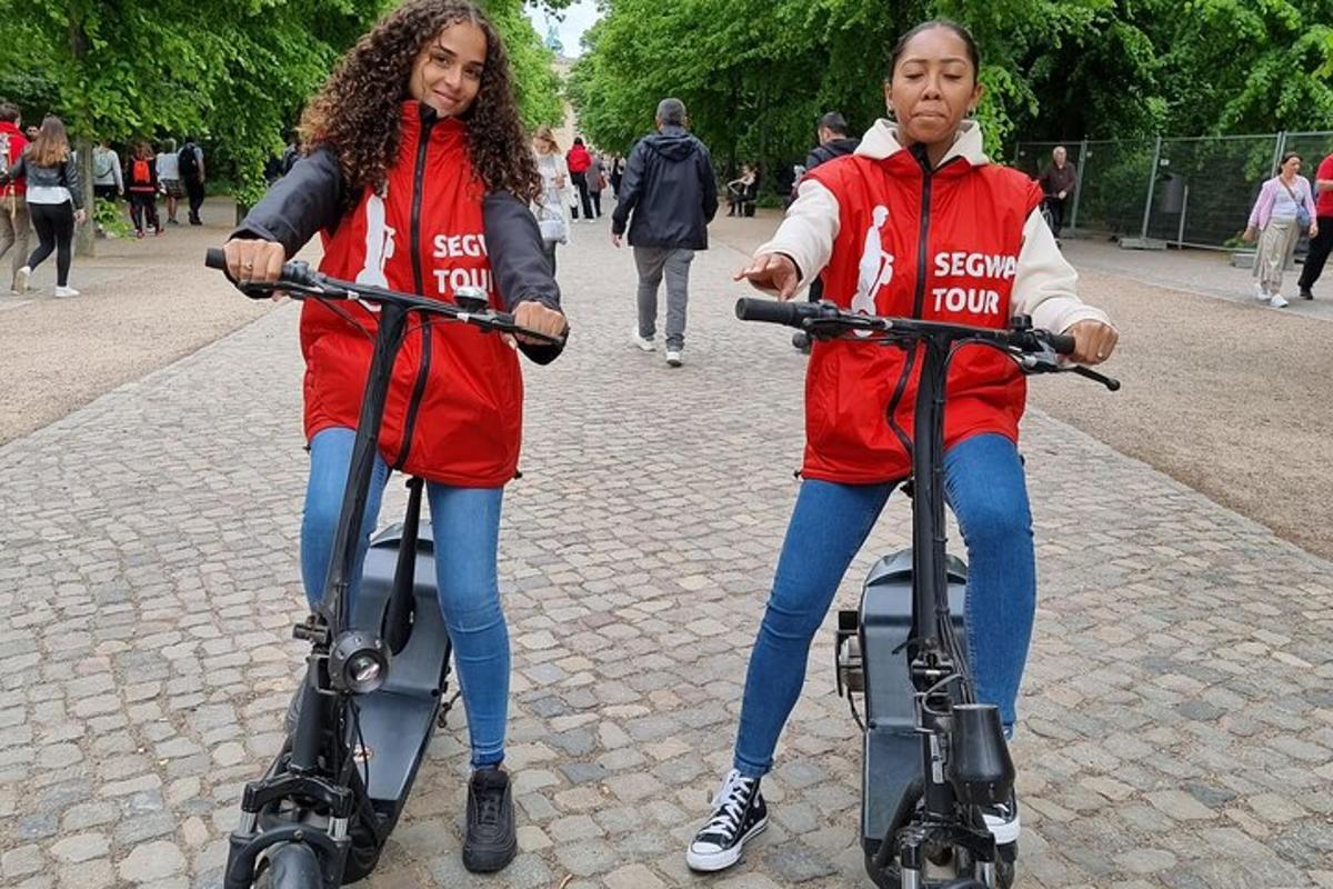 two people riding on scooters on a street