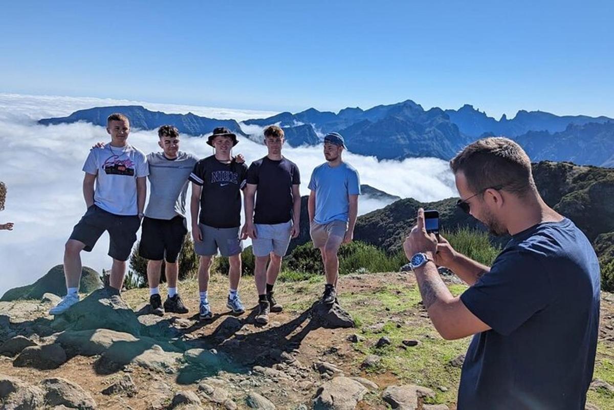 um homem tirando uma foto de um grupo de homens em pé em uma montanha