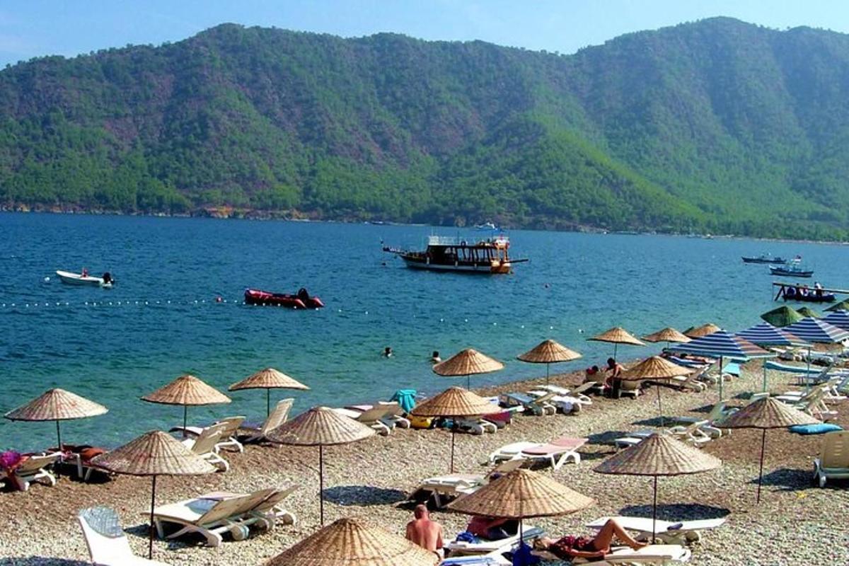paplūdimys su skėčiais ir valtimi vandenyje